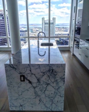 A Millennium Tower Boston condo unit features marble kitchen islands, Sub-Zero wine fridge and views of the Seaport District.