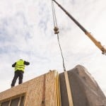 Roofer builder worker with crane installing structural Insulated Panels SIP.