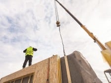 Roofer builder worker with crane installing structural Insulated Panels SIP.